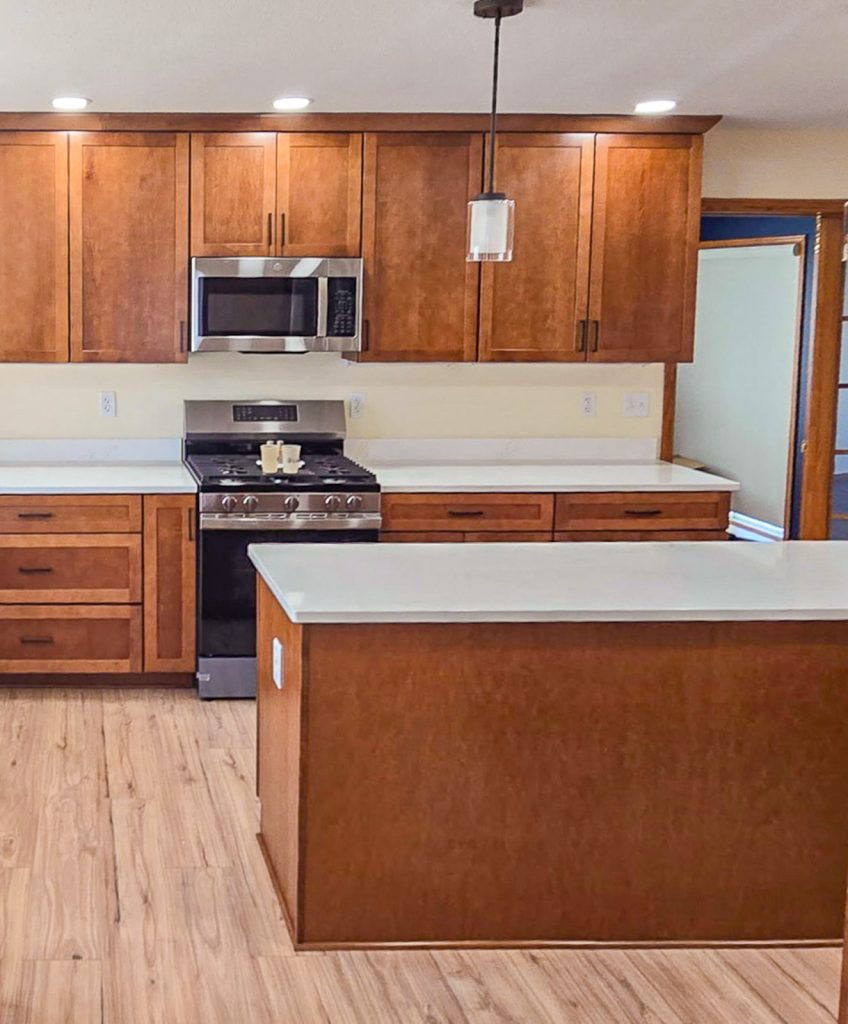 Warm Transitional - Elevated Designs: partial view of kitchen with wood cabinets and white counter