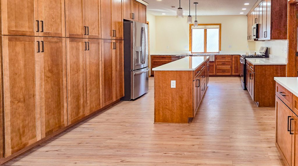 Warm Transitional - Elevated Designs: alternate side view of full kitchen with wood cabinets, stainless steel appliances, and wood floors