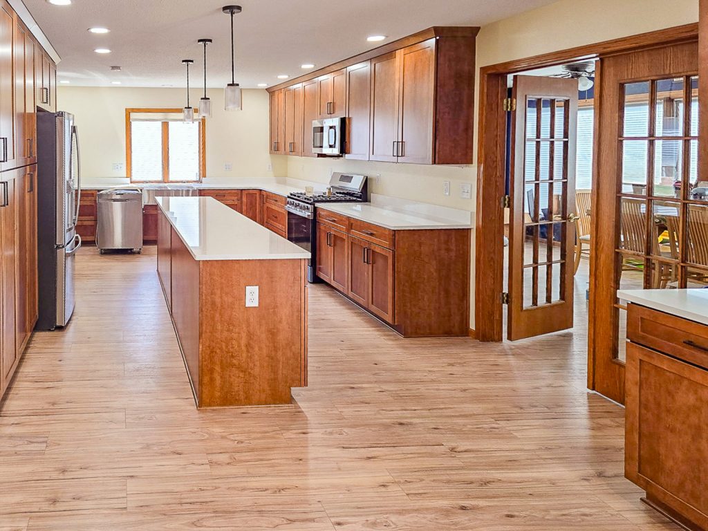 Warm Transitional - Elevated Designs: alternate side view of full kitchen with wood cabinets, stainless steel appliances, and wood floors
