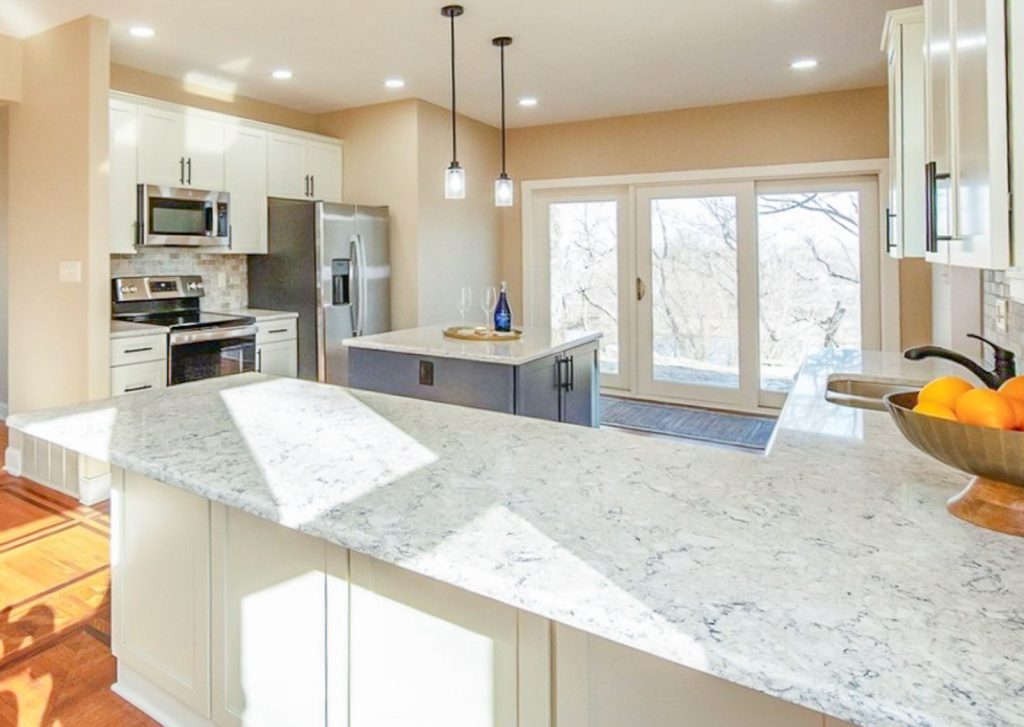 Transitional Charm - Elevated Designs: Full kitchen view of main white cabinet kitchen with marble counters, stainless steel appliances, and wood floors