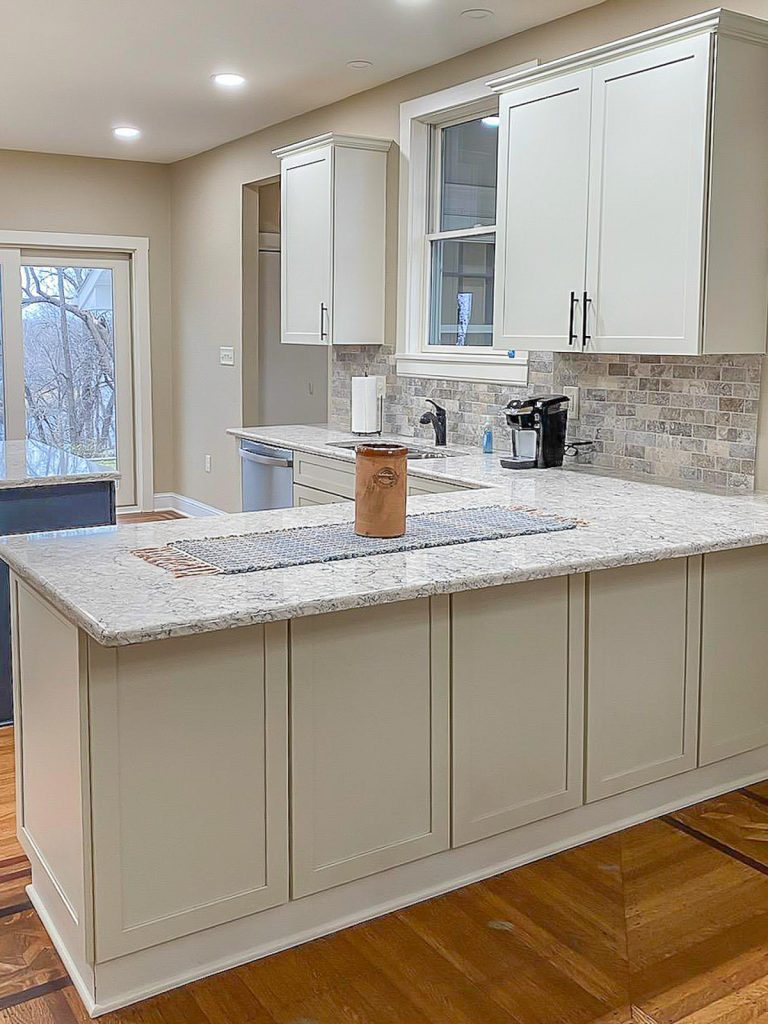 Transitional Charm - Elevated Designs: View of main white cabinet kitchen with marble counters, stainless steel appliances, and wood floors