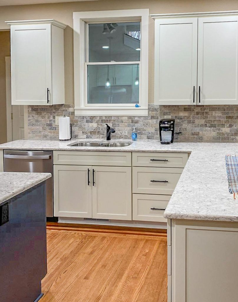 Transitional Charm - Elevated Designs: View of main white cabinet kitchen with marble counters, stainless steel appliances, and wood floors