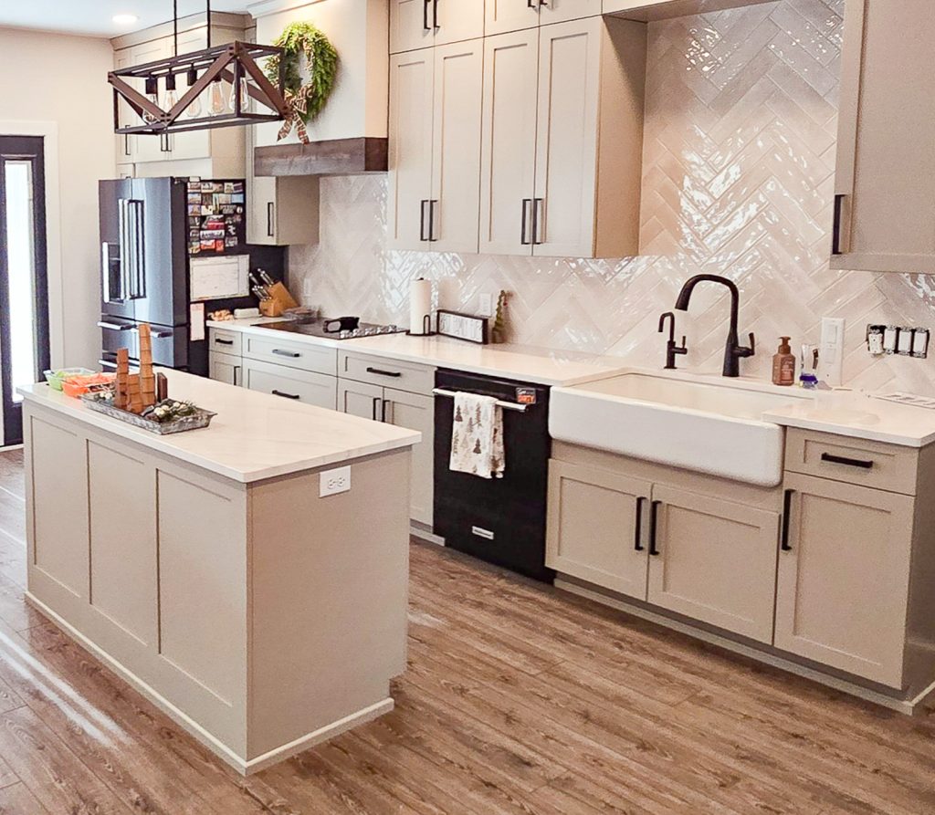 Modern Farmhouse - Elevated Designs: View of island and sink area of kitchen with white cabinets and wood floors