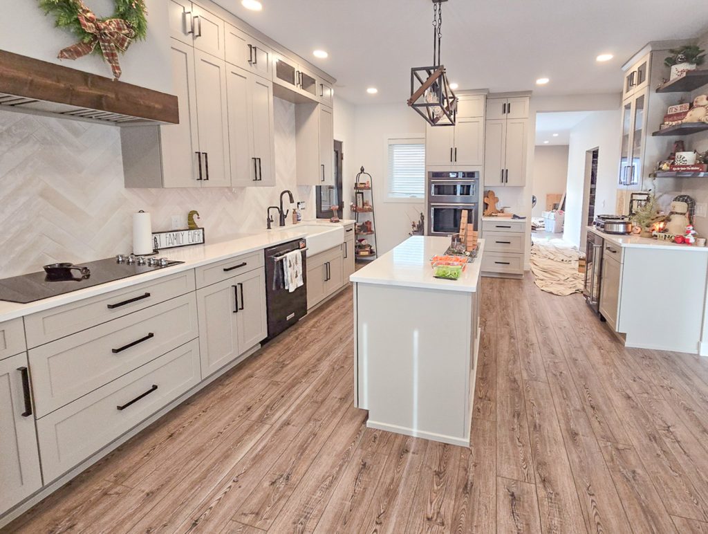 Modern Farmhouse - Elevated Designs: Full Kitchen with white cabinets, wood floors and stainless steel oven.