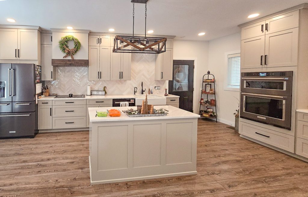 Modern Farmhouse - Elevated Designs: View of kitchen from behind the island with wood floors, white cabinets and stainless steel appliances