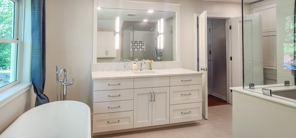 Timeless farmhouse - Elevated Designs: view of the vanity in the bathroom with white cabinets and large mirror