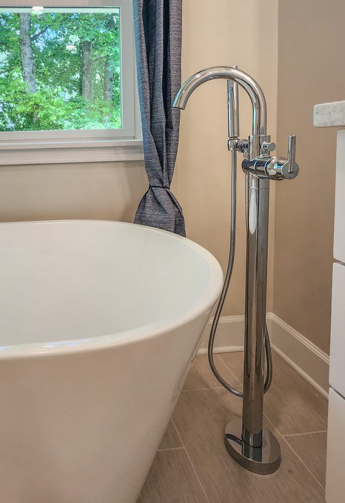Timeless farmhouse - Elevated Designs: closeup of white tub and its hardware