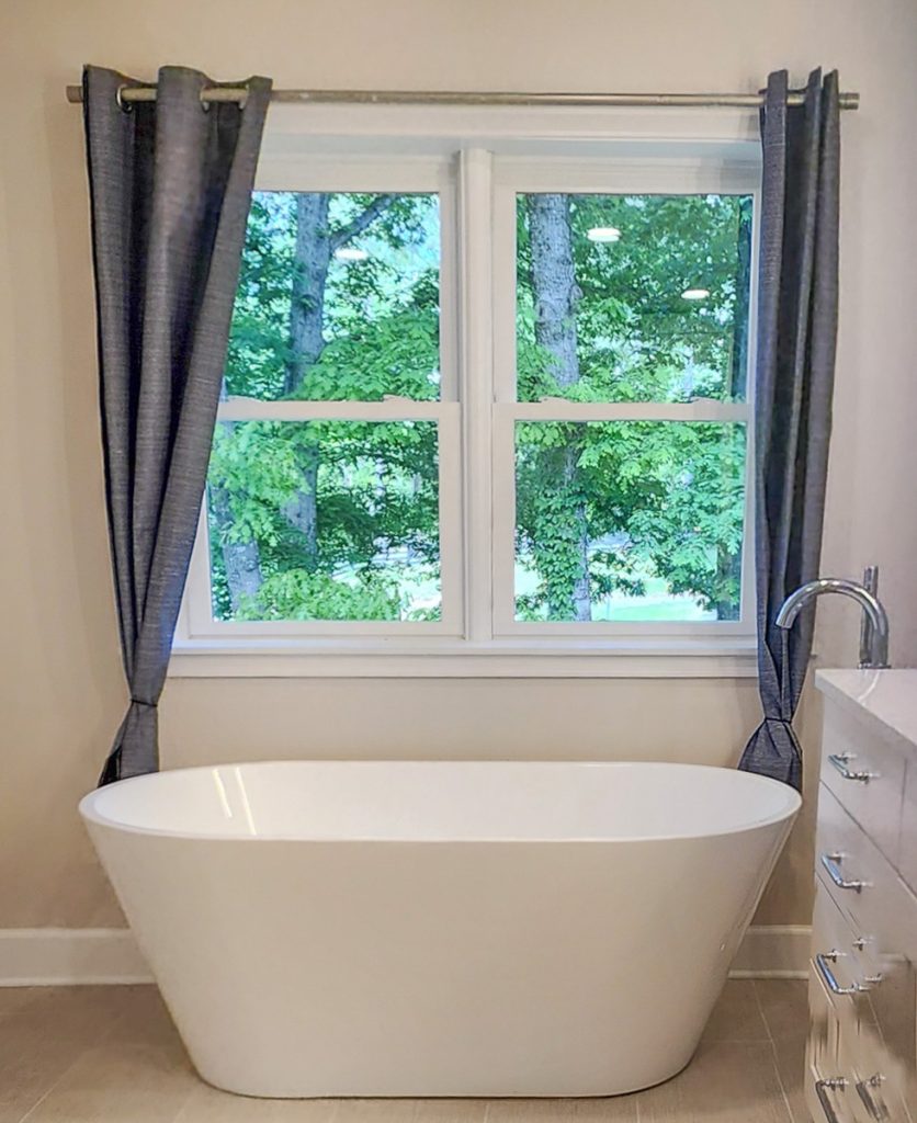 Timeless farmhouse - Elevated Designs: full view of white tub with window in background