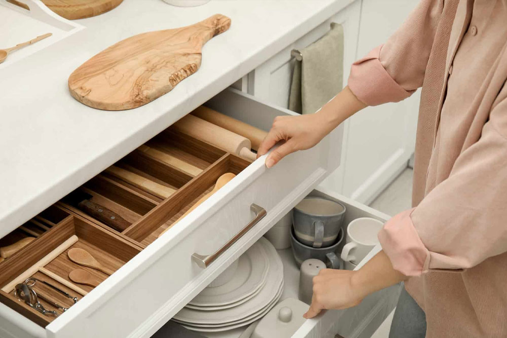 ElevatedDesigns_AttentionDetail person opening kitchen drawer. White cabinets and bamboo storage