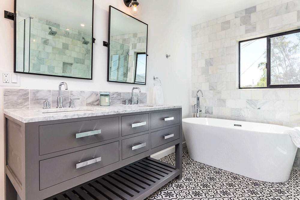 Elevated Designs Bathroom Designs bathroom with white tub and brown cabinetry. black and white tile on the floor